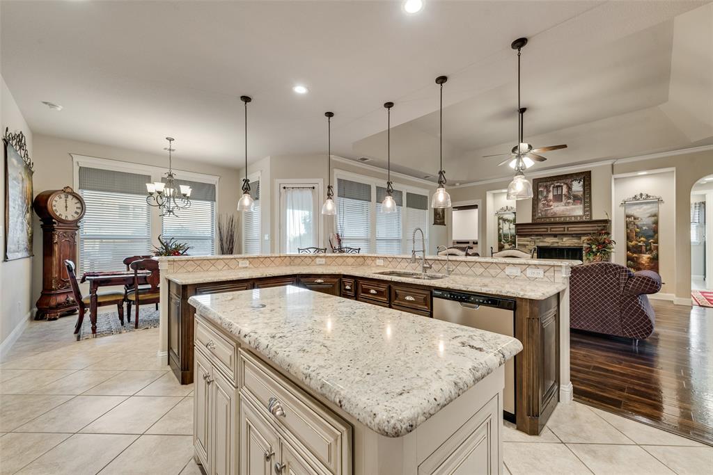 Kitchen featuring a center island, stone-surfaced countertops, custom cabinetry, recessed lighting, and pendant illumination
