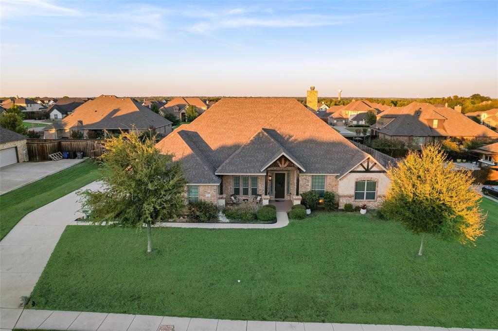 Single-story residence featuring a brick and stone exterior, a multi-gabled roofline, decorative timber framing, a concrete driveway, and mature landscaping