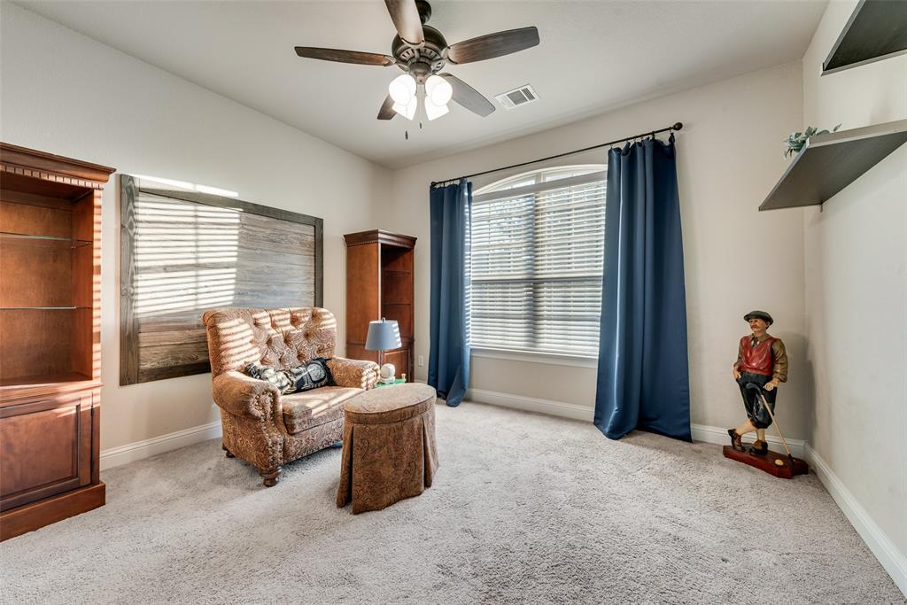 Room featuring high ceilings, wall-mounted wood shelving, built-in cabinetry, carpeted flooring, and a ceiling fan with integrated lighting