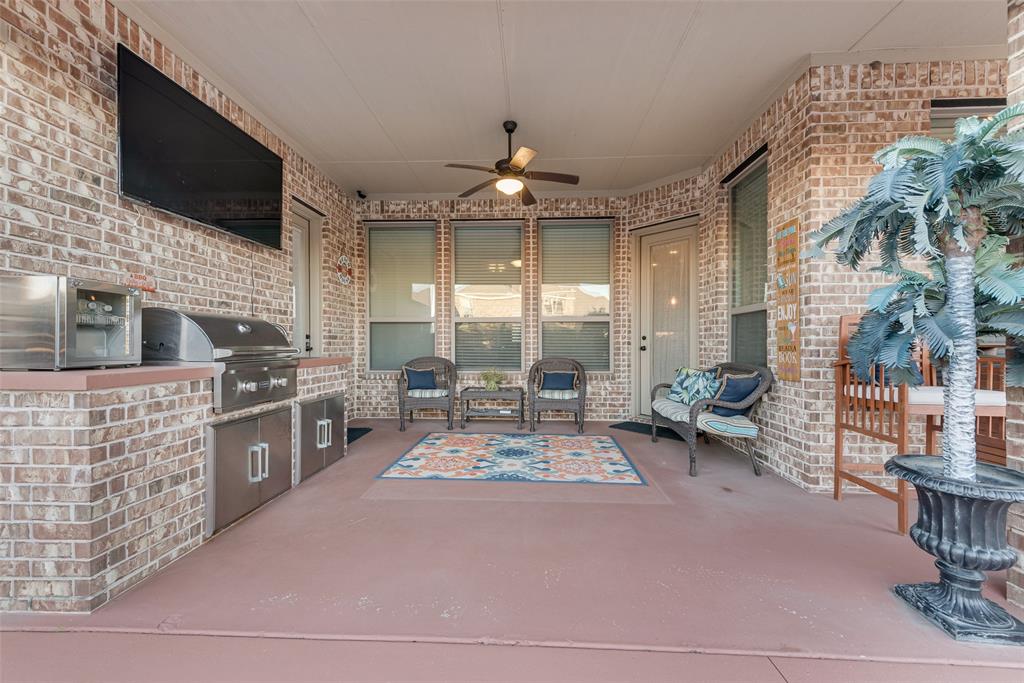 Covered patio featuring brick masonry, a built-in stainless steel outdoor kitchen with a grill and refrigerated storage, and a ceiling fan