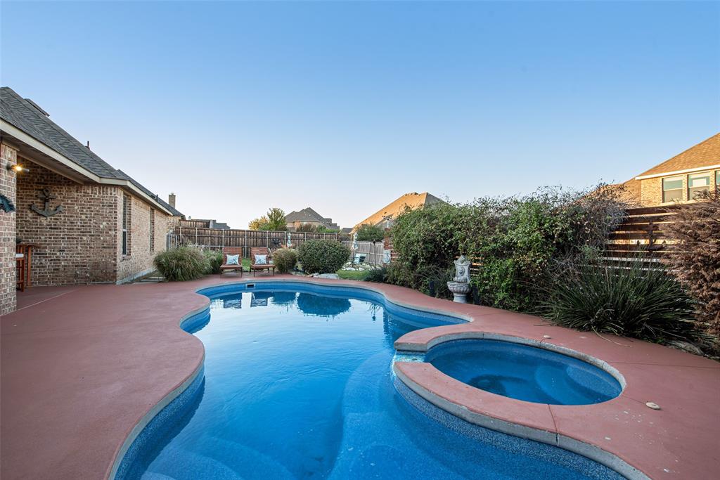Freeform swimming pool with integrated spa, masonry brick exterior, and covered patio area