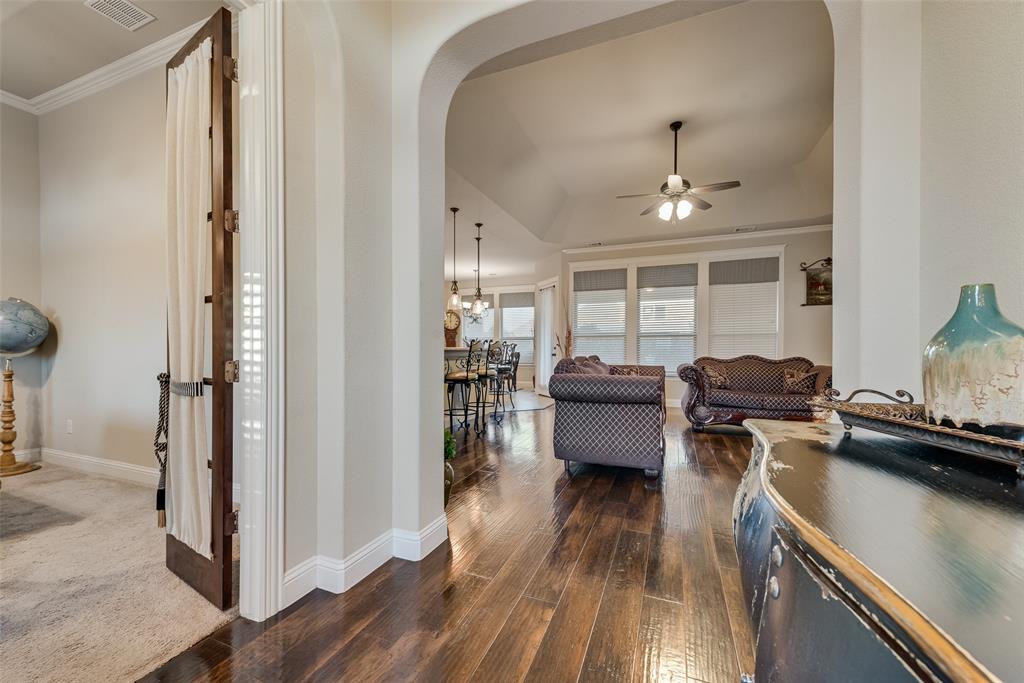 Interior featuring an arched entryway, wood-finish flooring, recessed tray ceiling, and a ceiling fan with integrated lighting