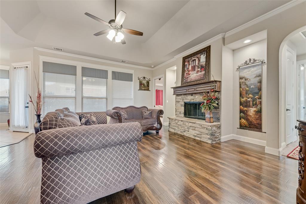 Vaulted ceilings, wood-finish flooring, stone-veneer fireplace with a wood mantel, and built-in recessed display shelving