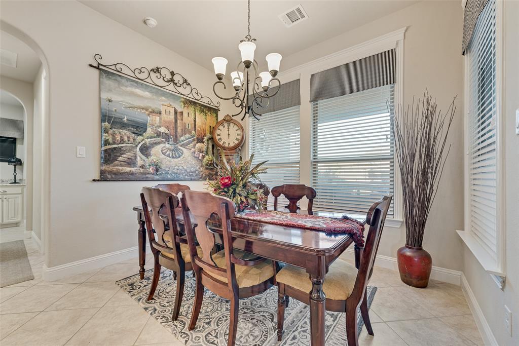 Dining area featuring large-format tile flooring, arched entryway, multi-light iron chandelier, and oversized windows with window treatments