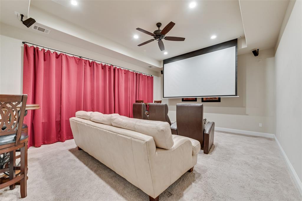 Media room featuring a retractable projection screen, ceiling fan, recessed lighting, and wall-mounted audio speakers