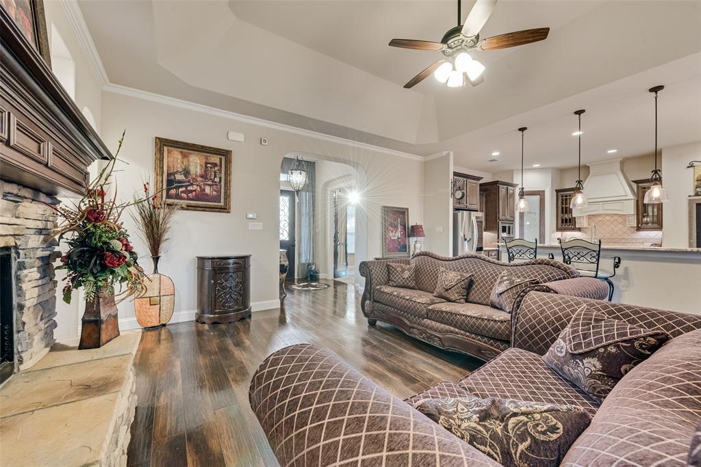 Living area featuring a vaulted ceiling, stone-surround fireplace with a wooden mantel, wood-finish flooring, and recessed lighting