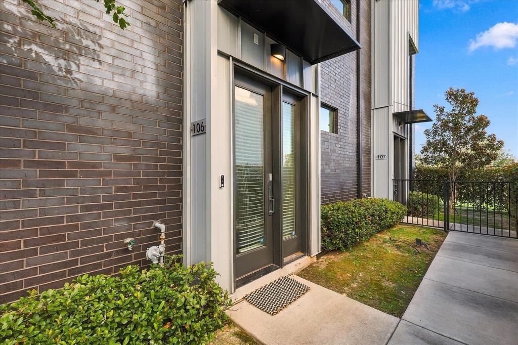 Contemporary exterior featuring dark brick masonry, vertical metal panel siding, a metal door awning, and a glass-paneled entry door