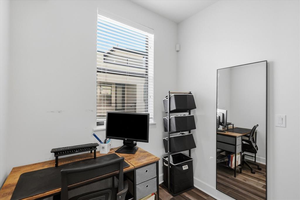 Room featuring a tall window with horizontal blinds and wood-finish flooring