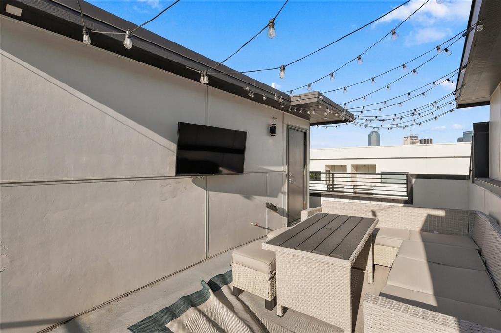Rooftop terrace featuring smooth stucco walls, metal railing, and overhead string lighting