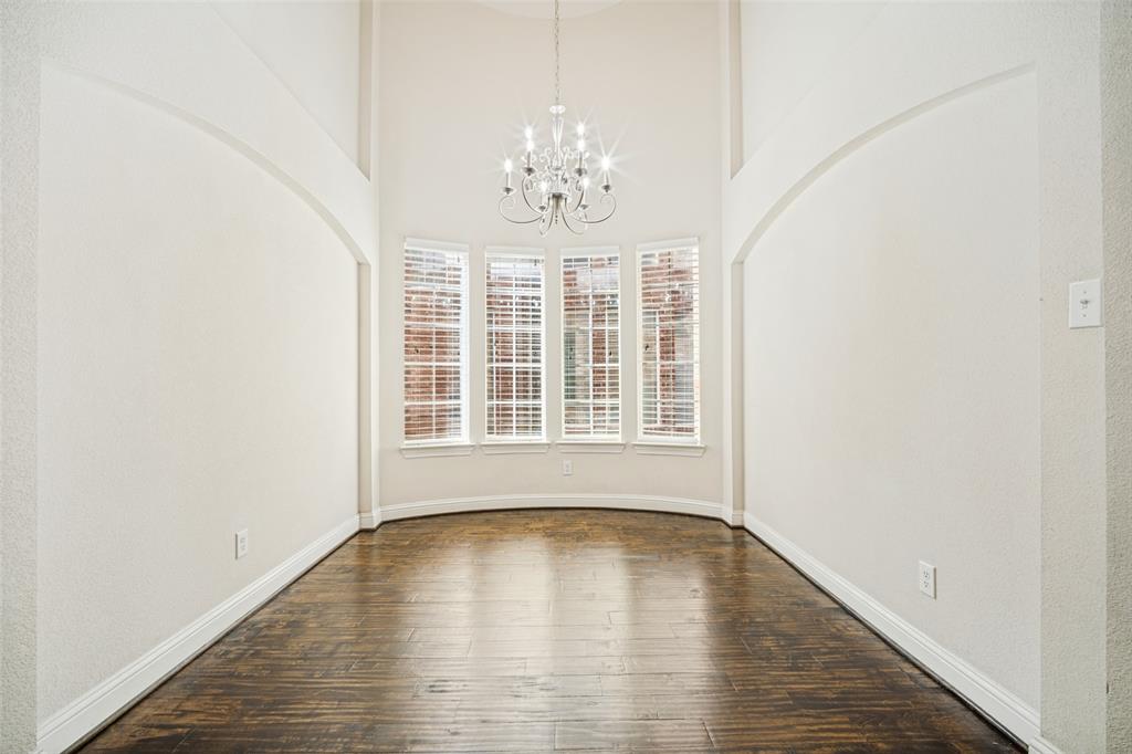 Vaulted ceilings featuring an arched architectural detail, multi-pane bay windows, wood-finish flooring, and a tiered chandelier Vaulted ceilings featuring an arched architectural detail, multi-pane bay windows, wood-finish flooring, and a tiered chandelier