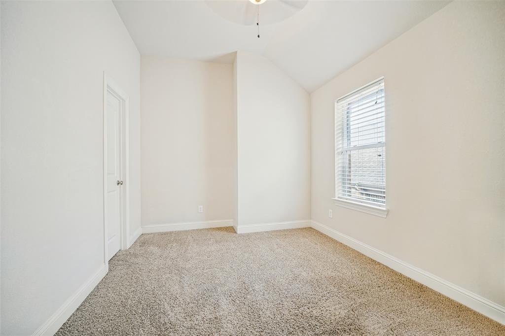 Interior space featuring vaulted ceilings, neutral wall tones, textured carpeting, and a window with horizontal blinds