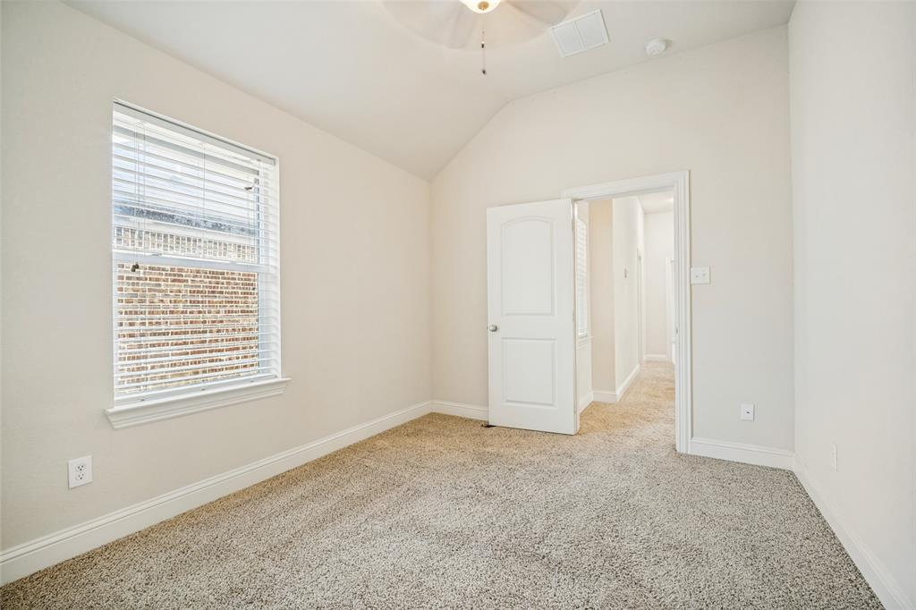Room featuring vaulted ceilings, neutral carpeting, a multi-pane window with adjustable blinds, and an integrated ceiling fan
