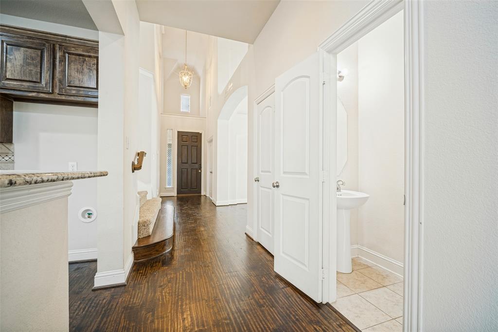 Entryway featuring wood-finish flooring, soaring ceilings, a multi-pane front door, a pendant chandelier, and a powder room with a pedestal sink