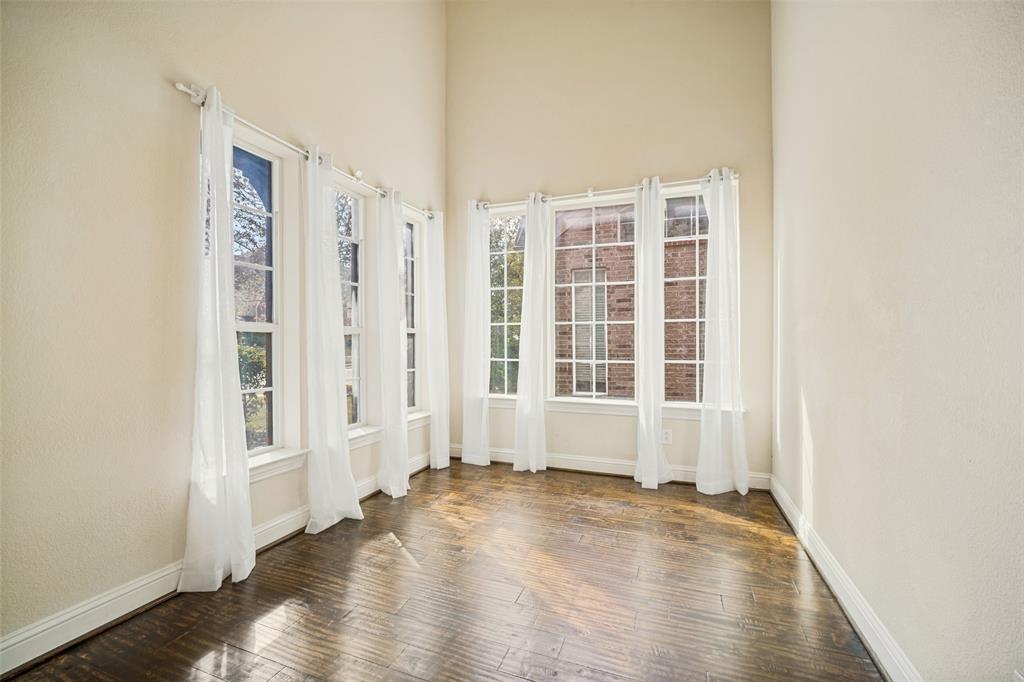 High-ceilinged room featuring wood-finish flooring and expansive windows with multi-pane grid detailing High-ceilinged room featuring wood-finish flooring and expansive windows with multi-pane grid detailing
