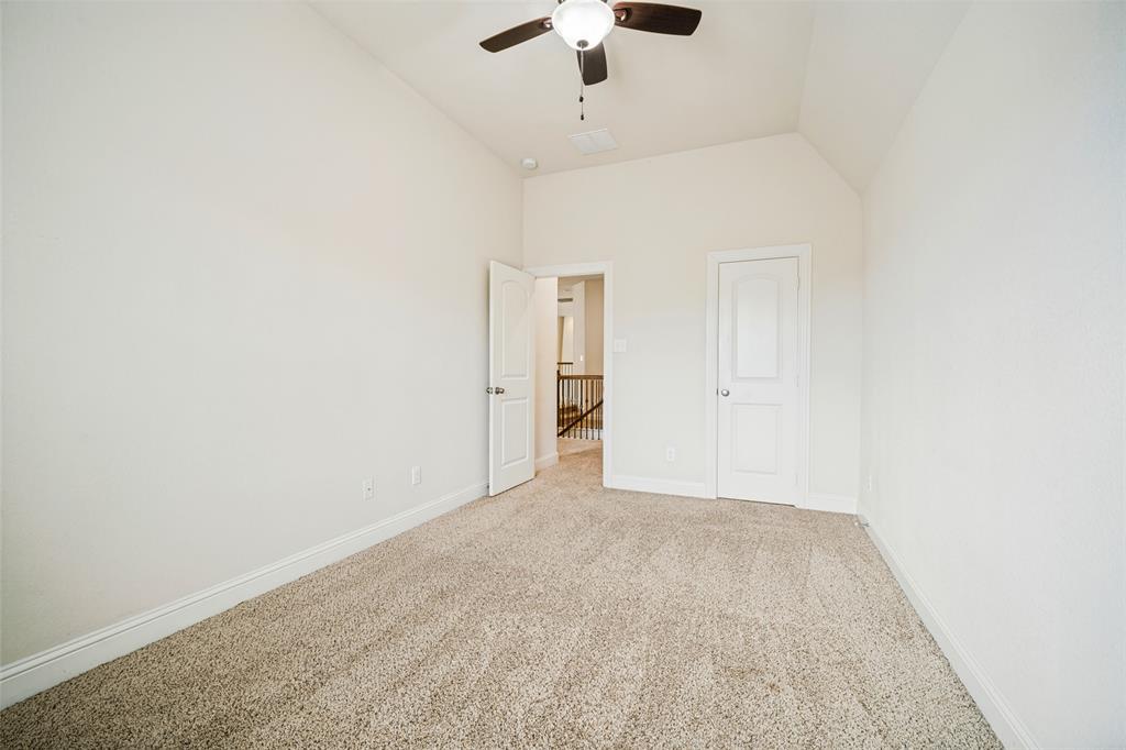 Vaulted ceiling featuring a central ceiling fan with integrated lighting, neutral wall-to-wall carpeting, and two interior doors with molded panel detailing