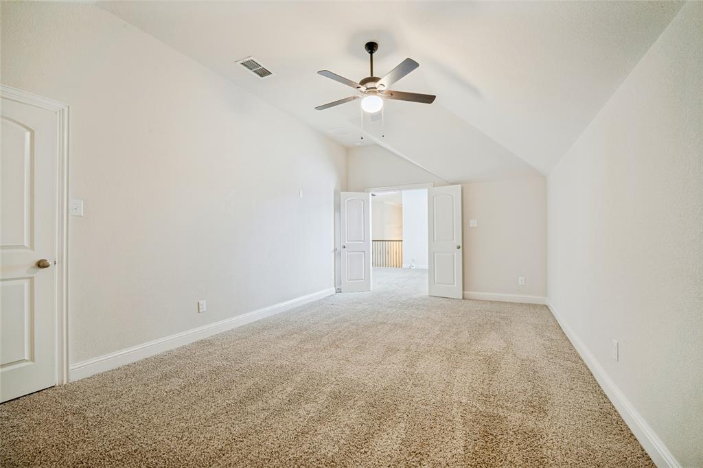 Vaulted ceilings, neutral carpeting, and a ceiling-mounted light fixture with a fan