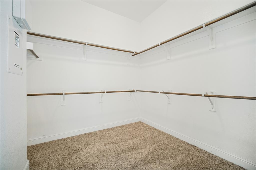 Walk-in closet featuring dual-tier shelving, neutral wall-to-wall carpeting, and integrated clothing rods