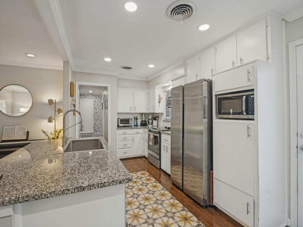 Kitchen featuring stone countertops, stainless steel appliances, white cabinetry, recessed lighting, and wood-finish flooring