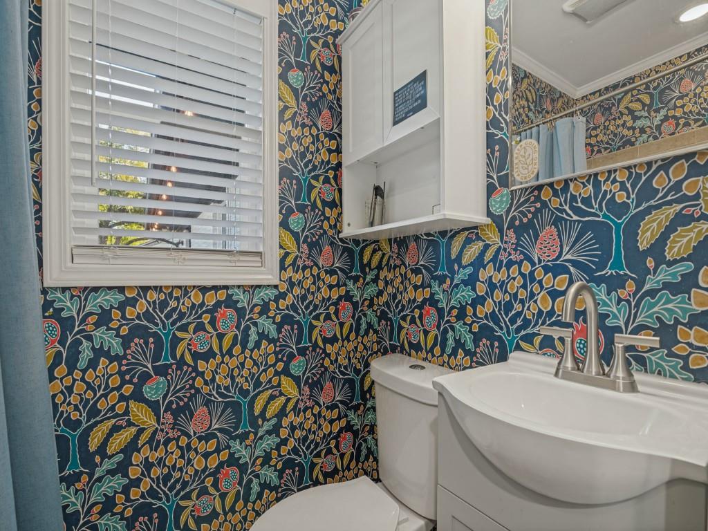 Bathroom featuring white cabinetry, integrated sink, metal faucet, framed window with blinds, and built-in wall storage