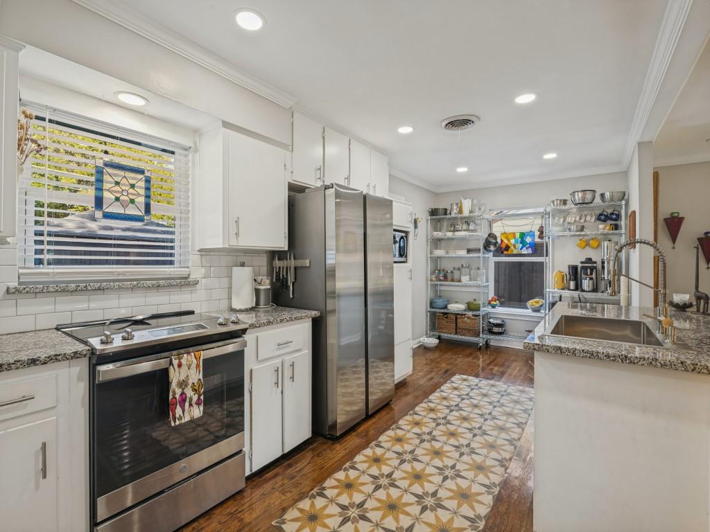 Kitchen featuring white cabinetry, stone countertops, subway tile backsplash, stainless steel appliances, and wood-finish flooring