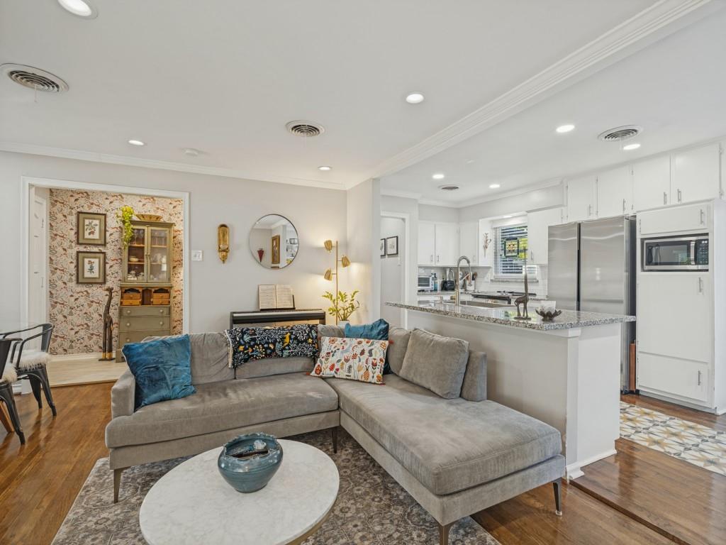 Kitchen featuring white shaker-style cabinetry, stone-surface countertops, and stainless steel appliances, complemented by wood-finish flooring and recessed lighting throughout