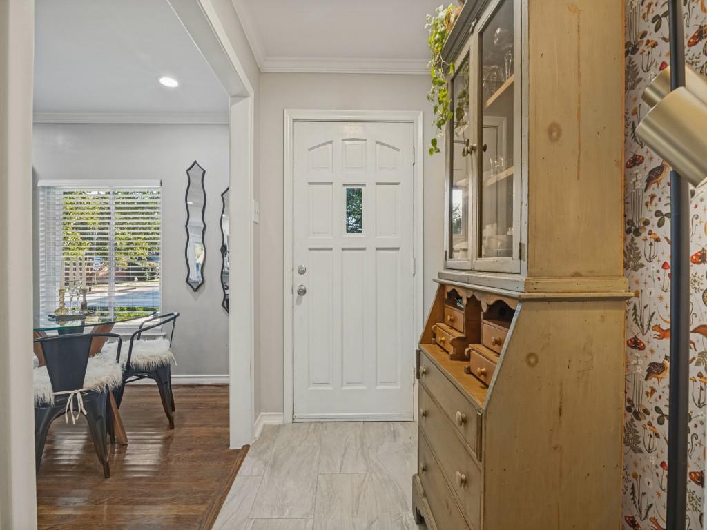 Entryway featuring neutral-toned tile flooring, recessed lighting, crown molding, and a white six-panel door with a central glass insert