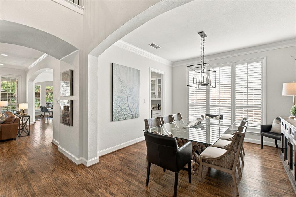 Wood-finish flooring, architectural archways, crown molding, plantation shutters, and a geometric metal chandelier