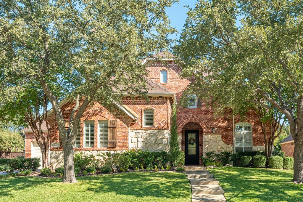 Traditional brick and stone masonry exterior with decorative herringbone brick detailing, arched entryway, and mature trees