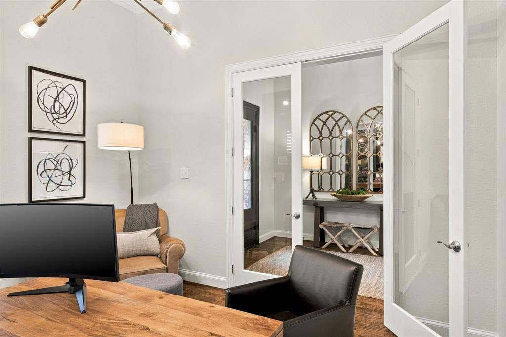 Room featuring wood-finish flooring, white French doors with glass panels, and a modern multi-arm chandelier with exposed filament bulbs
