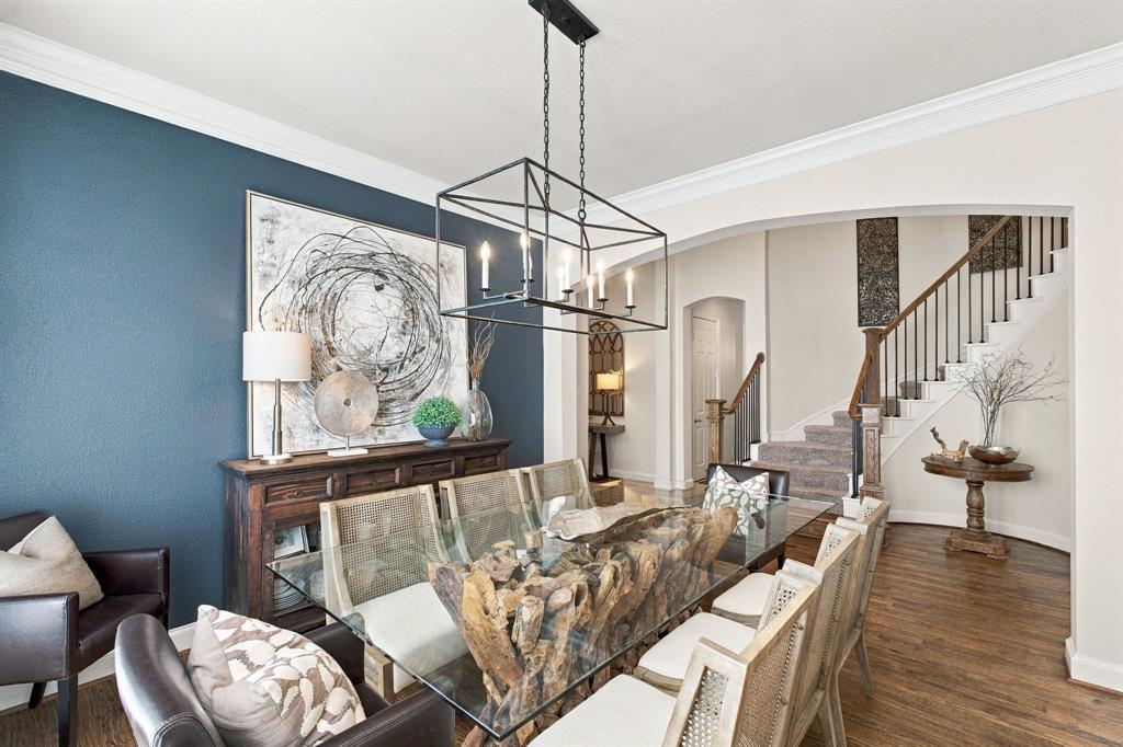Dining area featuring a dark blue accent wall, crown molding, wood-finish flooring, and a rectangular metal lantern-style light fixture, showcased beneath an arched entryway