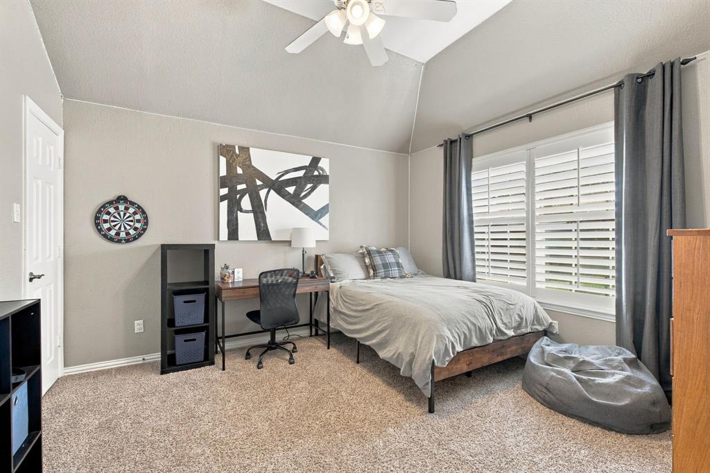 Vaulted ceiling with a central multi-blade ceiling fan, neutral wall tones, plush wall-to-wall carpeting, and interior window shutters