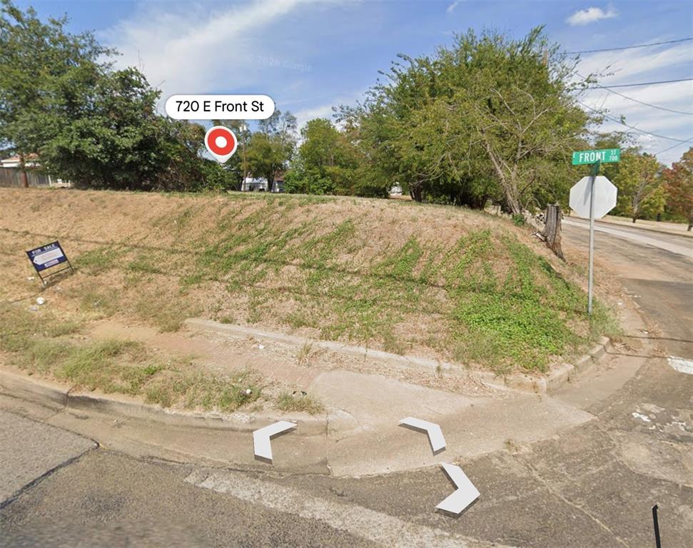 Corner lot featuring street-level concrete curb access, sidewalk infrastructure, and mature trees Corner lot featuring street-level concrete curb access, sidewalk infrastructure, and mature trees