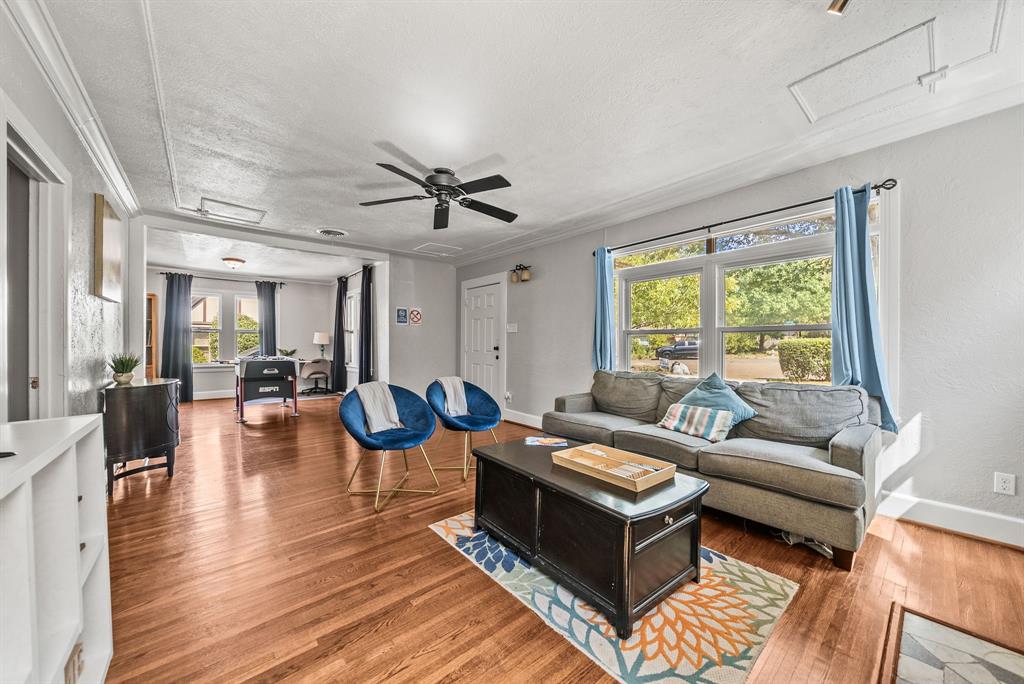 Hardwood flooring, crown molding, ceiling fan, and large windows