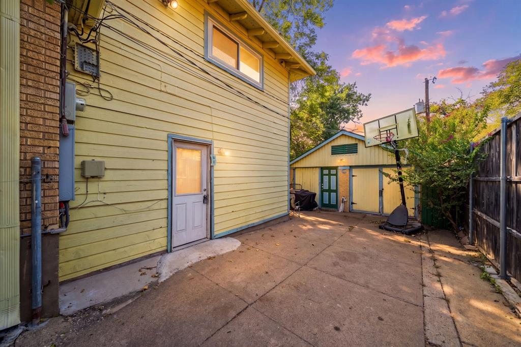 Paved concrete driveway with a detached auxiliary building featuring a double entry door and a separate utility door