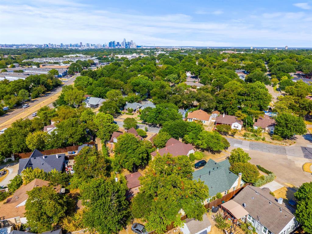 Residential neighborhood featuring mature trees and a distant city skyline