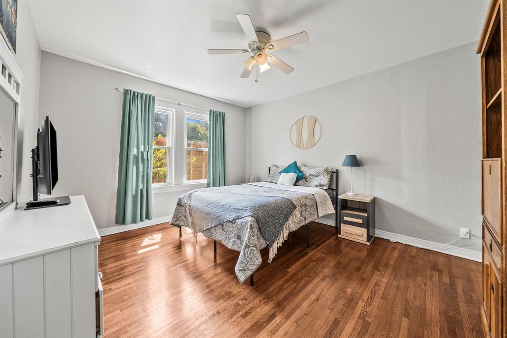 Hardwood flooring, light gray walls, white trim, ceiling fan, and large windows