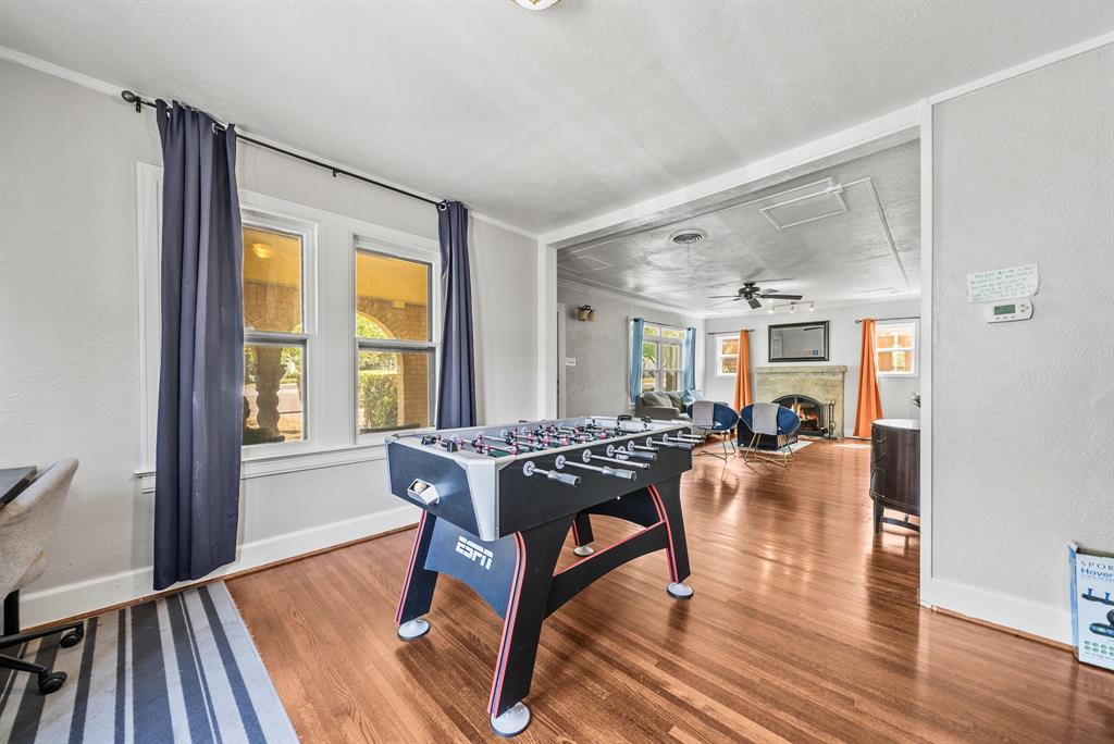 Wood-finish flooring extending throughout, multiple windows with natural light, and a living area featuring a stone fireplace