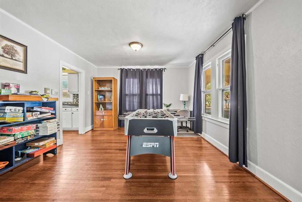 Hardwood flooring throughout, multiple windows with natural light, recessed lighting, and an open doorway leading to an additional room