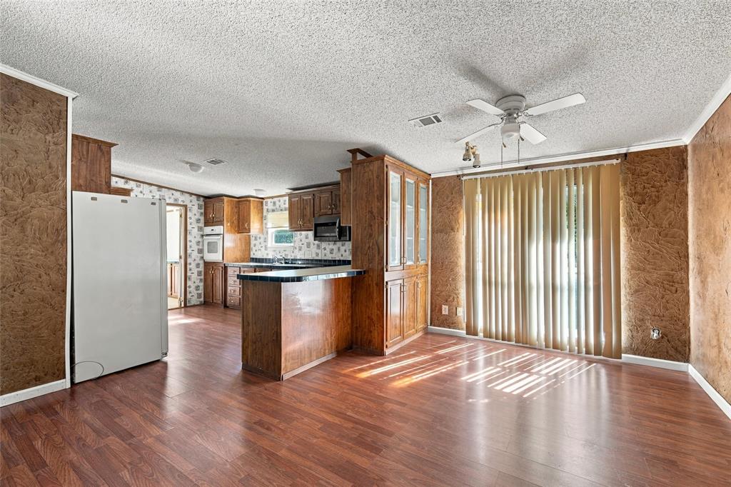 Kitchen area featuring wood-finish cabinetry, a breakfast bar, integrated wall oven, and wood-finish flooring