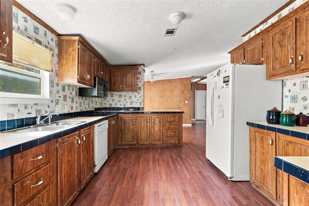 Kitchen featuring stained wood cabinetry, wood-finish flooring, dual-basin stainless steel sink, tile countertops, and built-in microwave