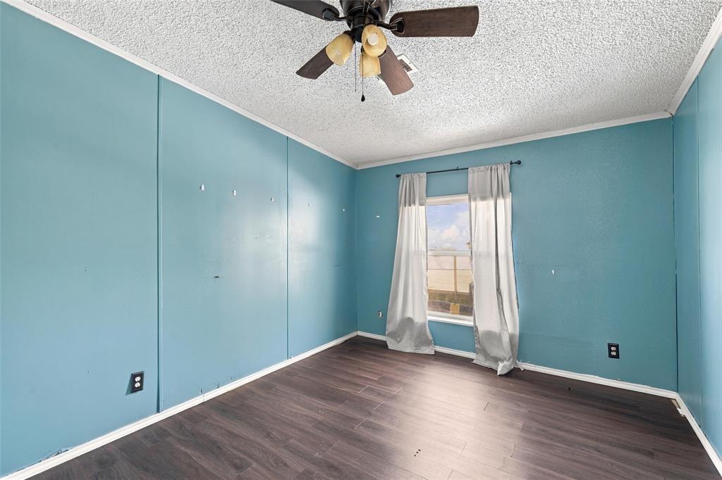 Room featuring wood-finish flooring, textured ceiling, and a ceiling-mounted light fixture with a fan