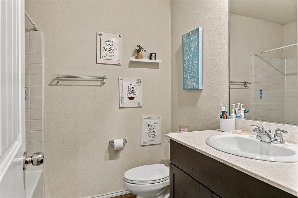 Bathroom featuring a dark-finish vanity, solid-surface countertop with an integrated oval sink, chrome-finish faucet, and a large wall-mounted mirror