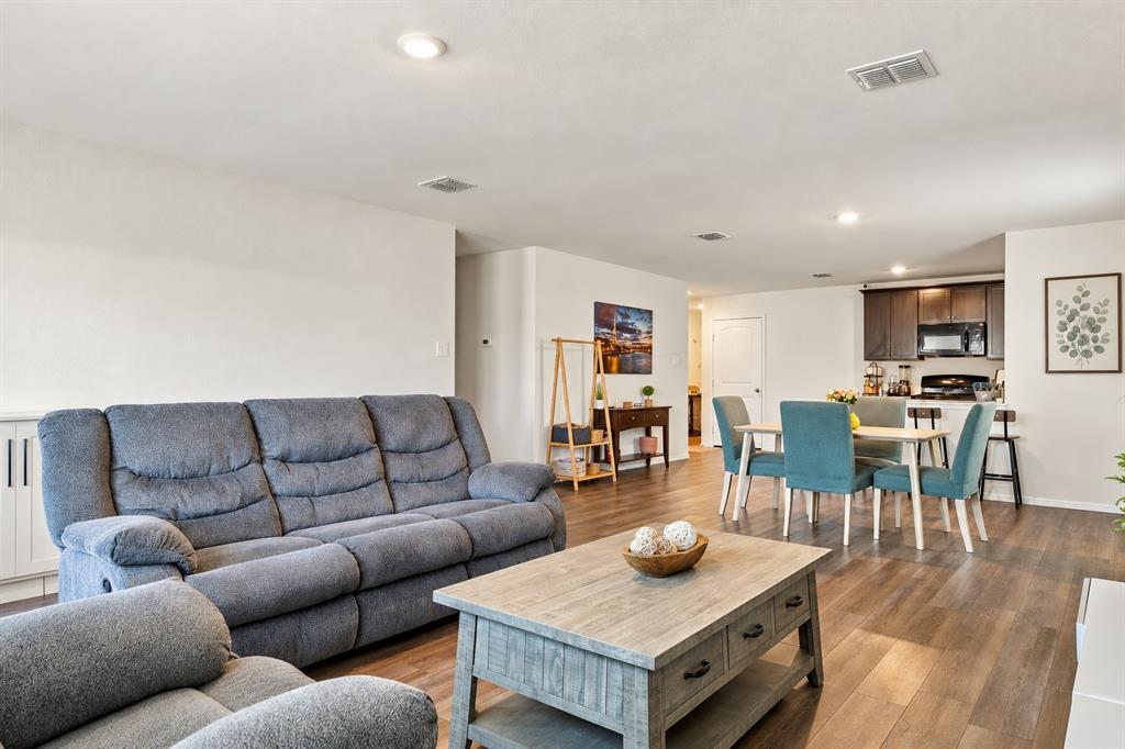Open concept interior featuring wood-finish flooring, recessed lighting, and kitchen cabinetry with a dark finish