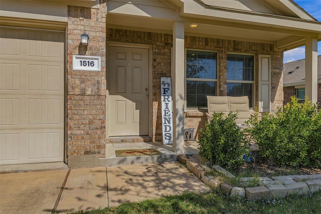 Brick façade exterior featuring a covered front porch, stone-bordered landscaping, and a multi-panel garage door