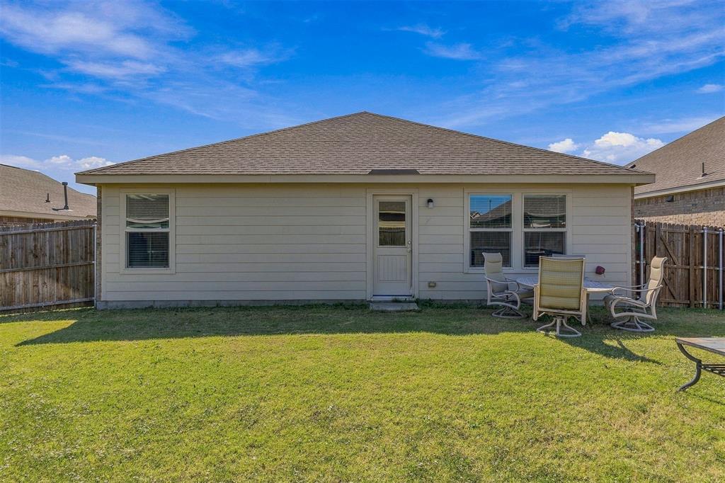 Rear exterior featuring horizontal siding, a hipped roof with asphalt shingles, double-pane windows, and a privacy wood fence