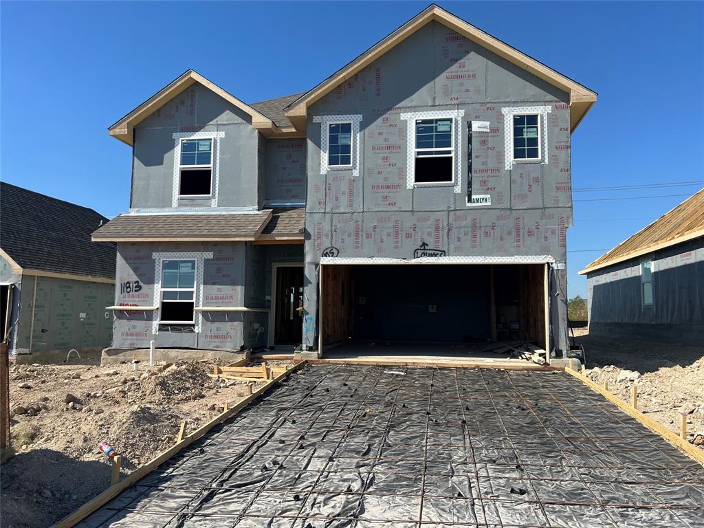 Two-story residential structure featuring a gable roof, multiple sash windows, and an attached two-car garage with a prepared concrete foundation Two-story residential structure featuring a gable roof, multiple sash windows, and an attached two-car garage with a prepared concrete foundation