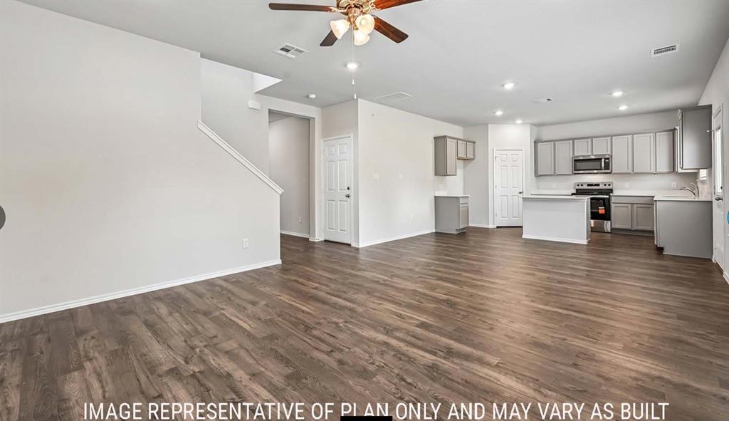 Open-concept main level featuring wood-finish flooring, kitchen with central island, stainless steel appliances, and ceiling fan with integrated lighting Open-concept main level featuring wood-finish flooring, kitchen with central island, stainless steel appliances, and ceiling fan with integrated lighting