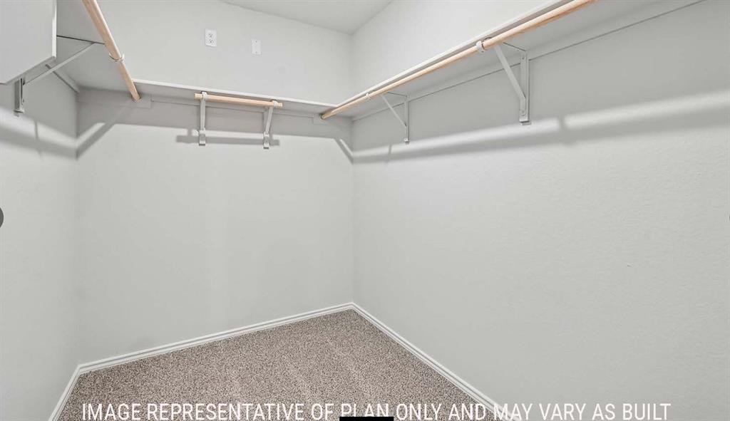 Walk-in closet featuring neutral carpeting and multi-tier wire shelving with integrated rods