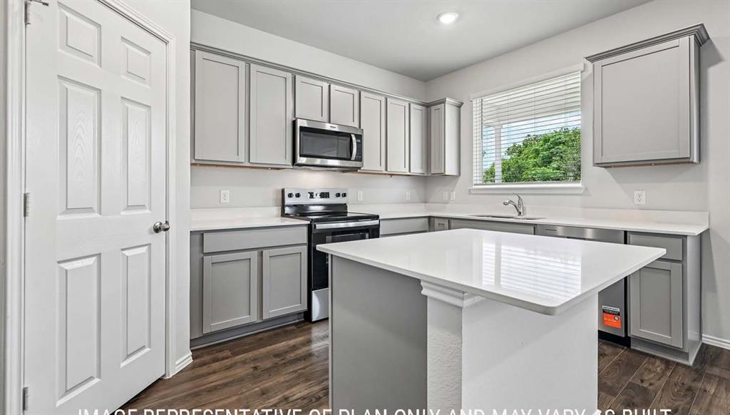 Kitchen featuring gray cabinetry, solid-surface countertops, center island, stainless steel microwave, and wood-finish flooring Kitchen featuring gray cabinetry, solid-surface countertops, center island, stainless steel microwave, and wood-finish flooring