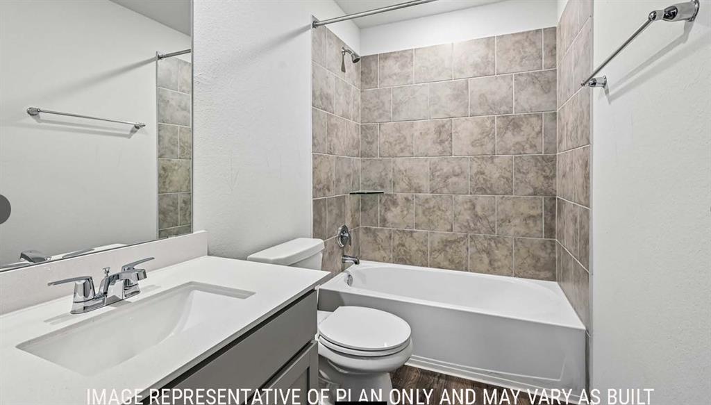Full-width mirror, vanity with a white countertop and undermount sink, shower-tub combination with full-height tile surround, and wood-finish flooring